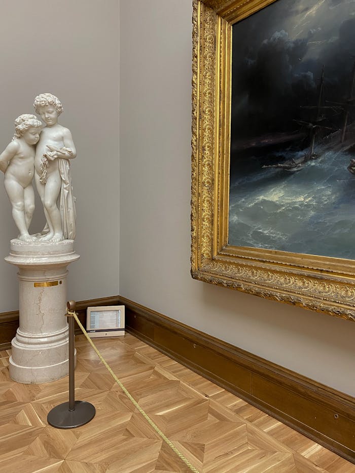 A museum hall showcasing a marble statue and a framed ocean painting.